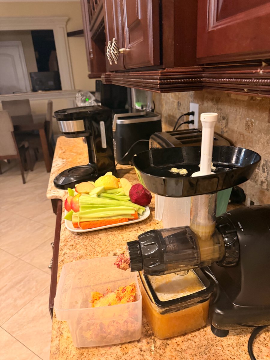 Ivan's Omega juicer on his kitchen counter with celery, carrots, apples and fresh juice
